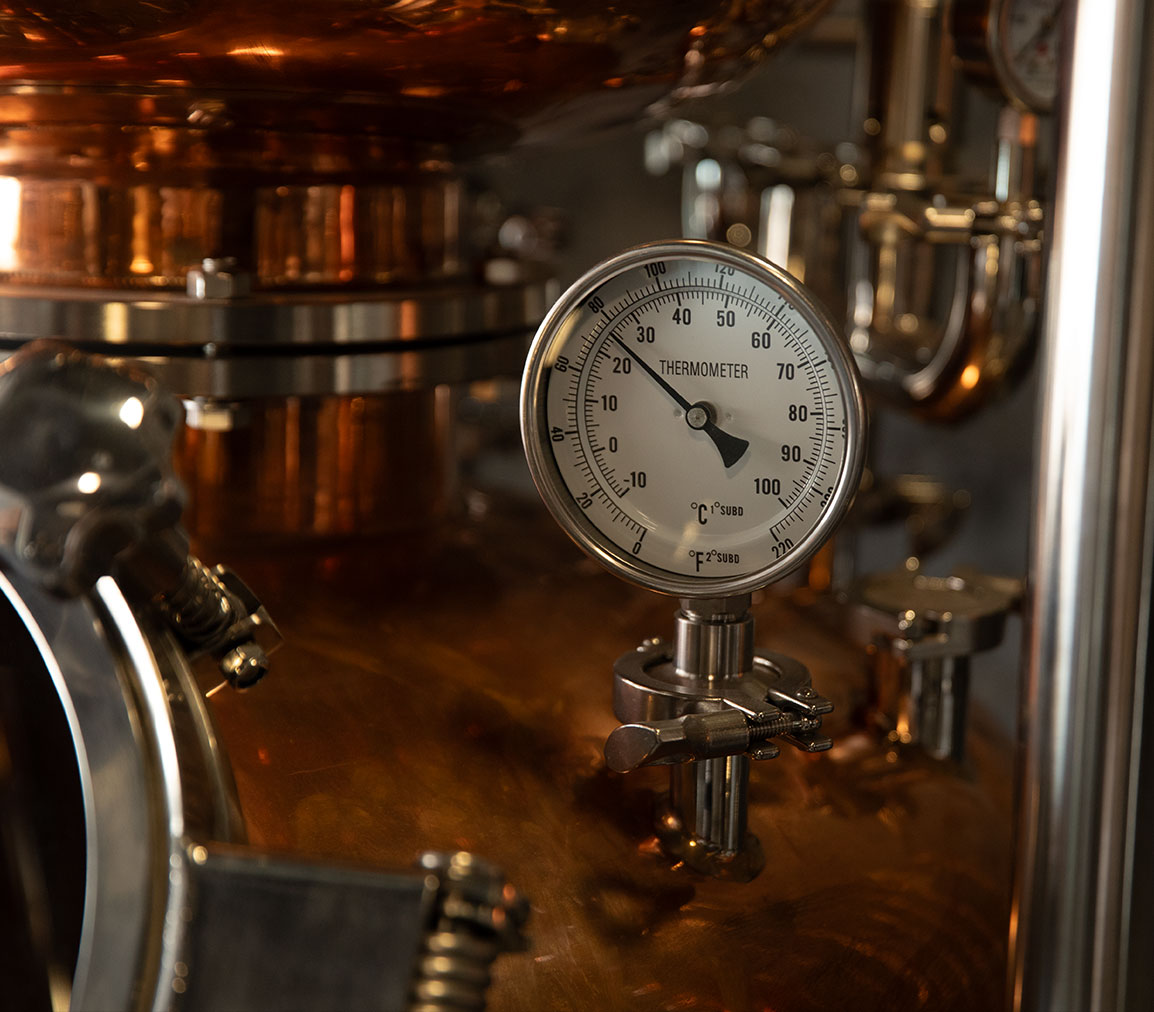 Close-up of a thermometer gauge on a copper distillation still at Opus Distillery in Laos