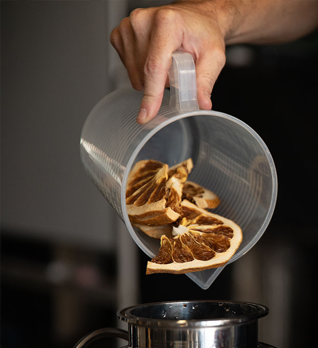 Distiller pouring dried citrus botanicals into the still during Opus Gin production process in Laos