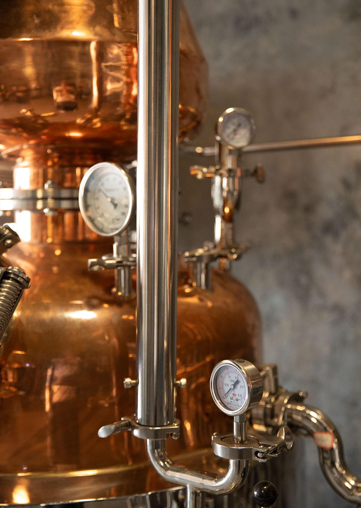 Copper pot stills with pressure and temperature gauges at Opus Distillery gin production facility in Laos