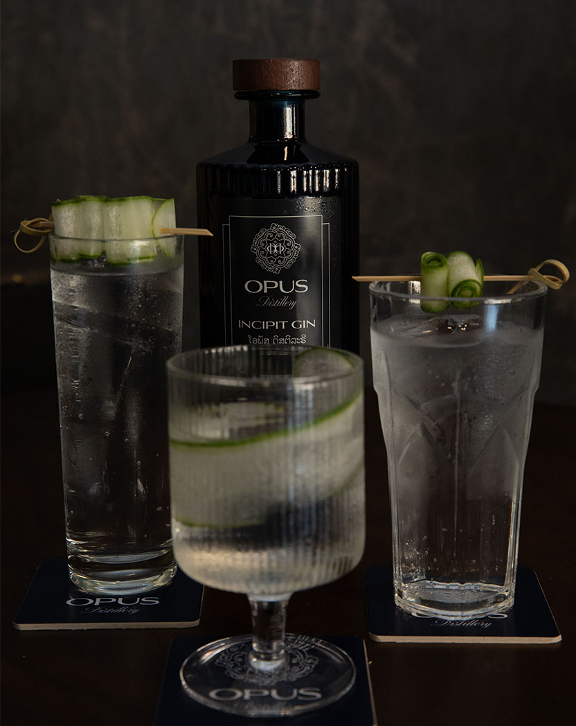 Three Opus Distillery Incipit Gin and tonic cocktails with cucumber garnish served on Opus branded coasters